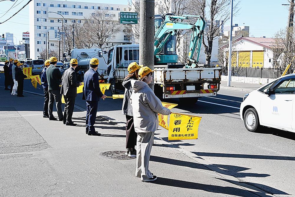 黄旗を持ち交通安全を呼び掛ける自販連札幌支部の職員ら