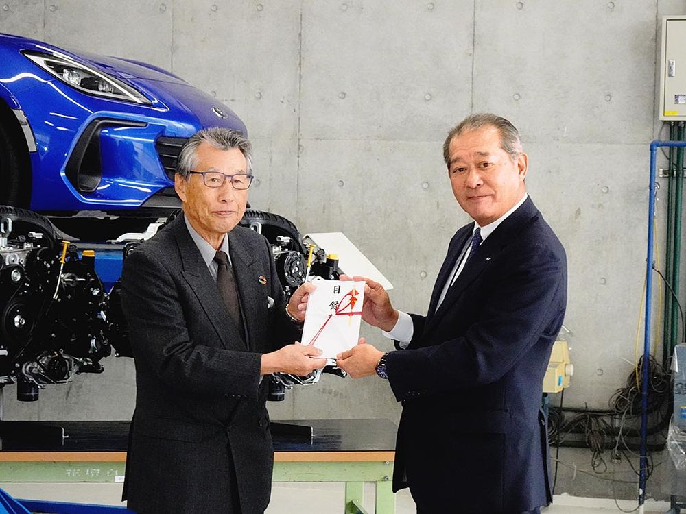 花壇自動車大学校で蛯名校長(左)に目録を渡す小笠原社長