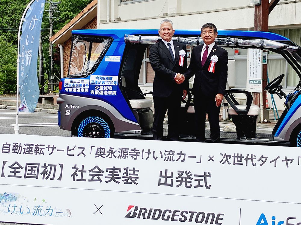 出発式で記念写真に納まる小椋市長（右）とブリヂストンの蓮沼常務役員
