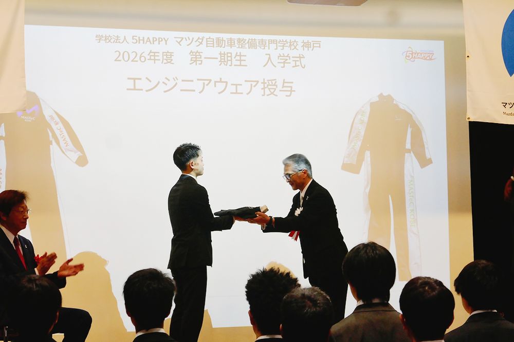 まっさらなエンジニアウエアが山本校長から新入生へ手渡された