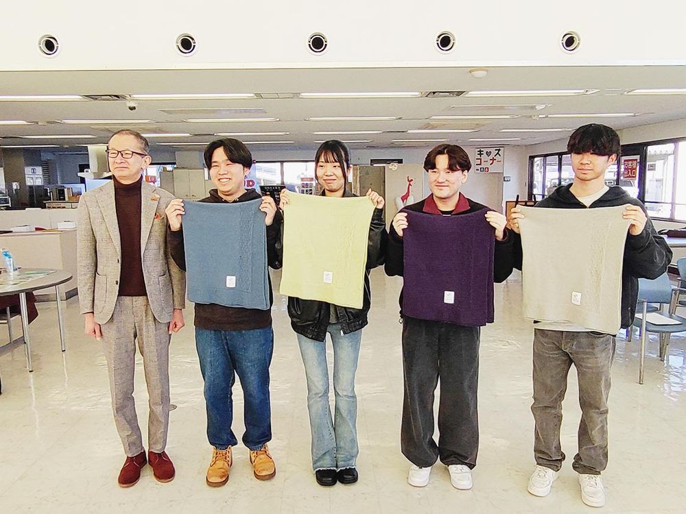最優秀作品に選ばれたフェザーコットンブランケットを手にする富山国際大学の学生と黒澤敏社長（左端）