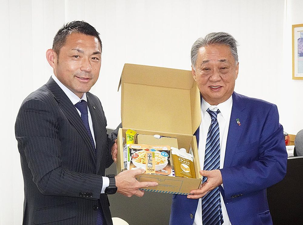 角川理事長（右）に防災キットを手渡す所賀支店長