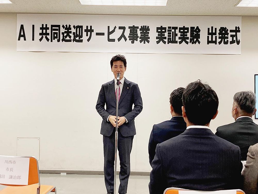 実証実験の出発式であいさつする越田市長