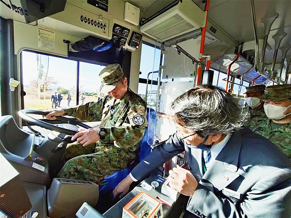 バス事業者の担当者(右)の指導を受けながら、ハンドルや機器の操作に挑む自衛官