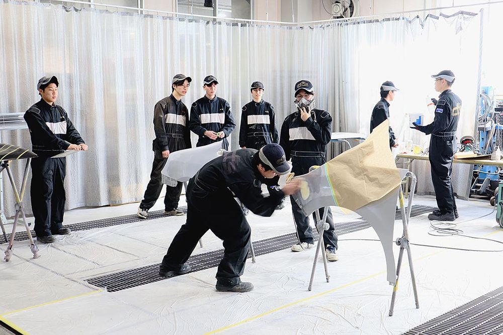 チームが協力して板金塗装の修理作業を実演
