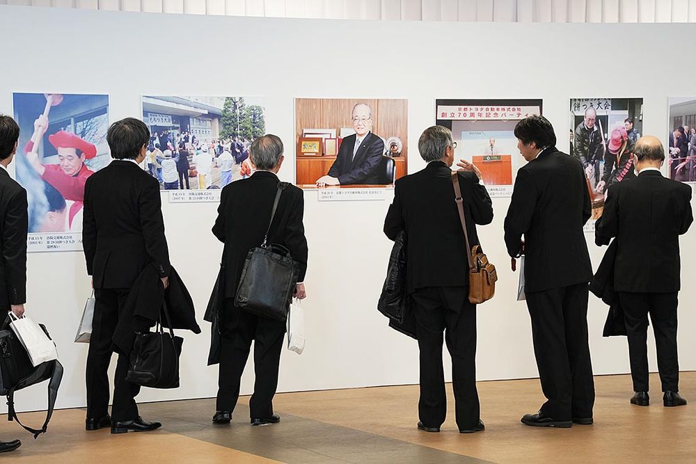 故人の写真について語り合う参列者ら