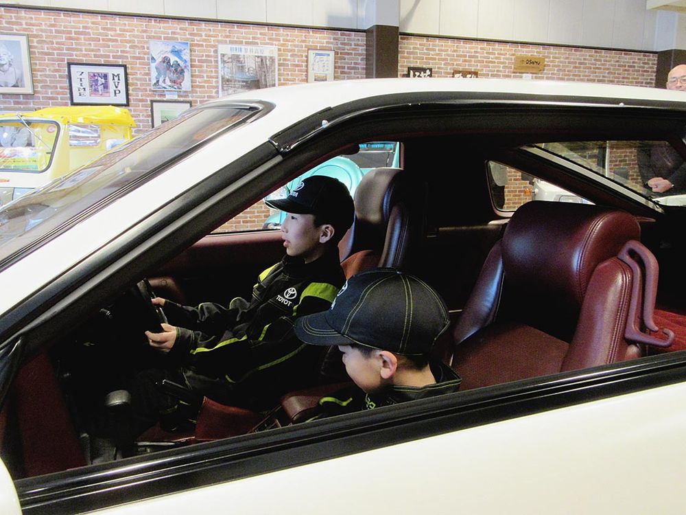 同社が２０２２年にレストアした高市早苗首相の元愛車トヨタ「スープラ」（１９９１年式）に乗り込む参加者
